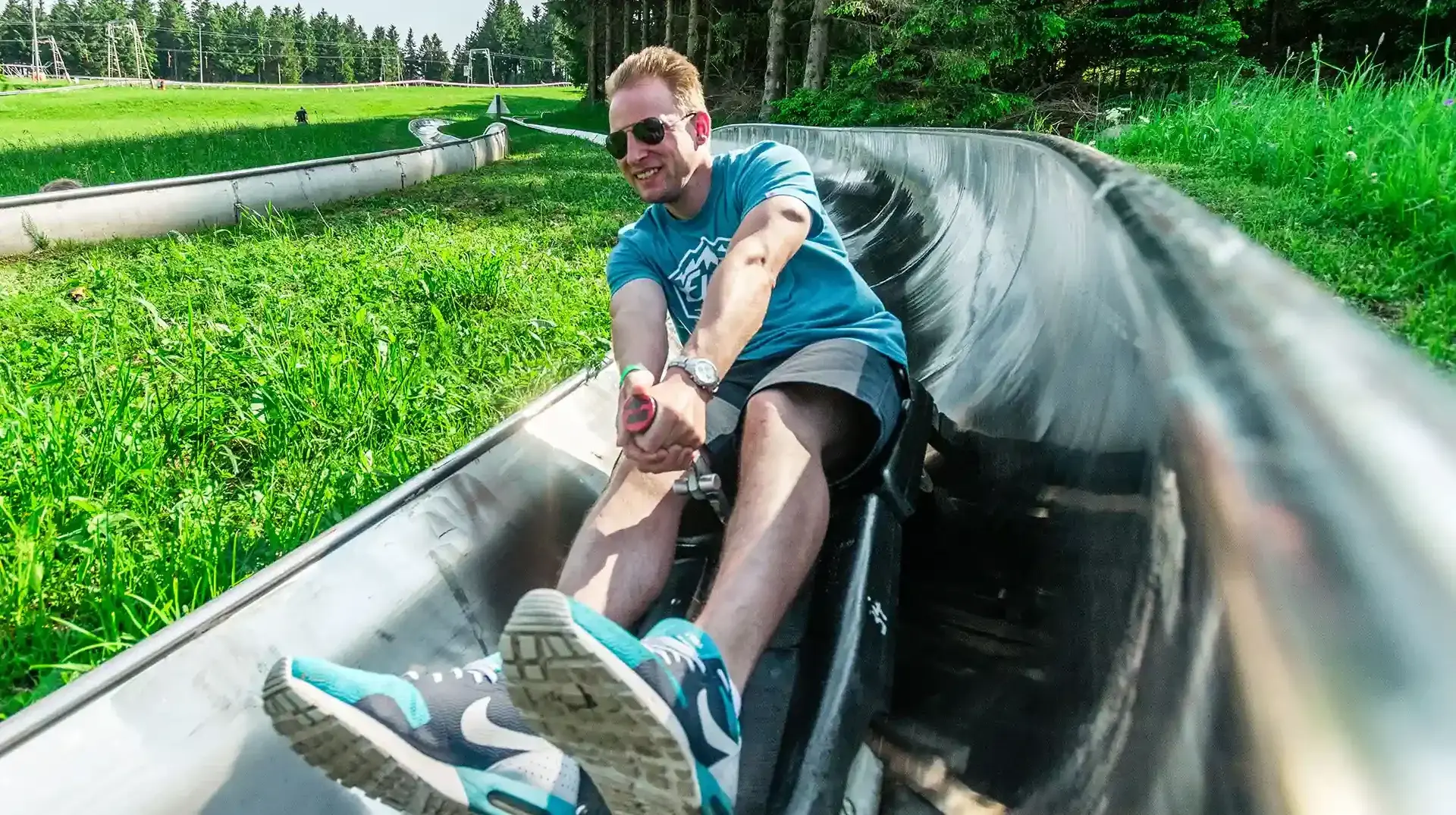 firmenevents-altenberg-erzgebirge-sachsen-11.webp Ein Mann fährt sichtlich erfreut mit der Sommerrodelbahn am Erlebnisberg Altenberg.