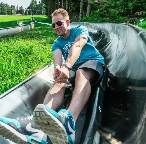 firmenevents-altenberg-erzgebirge-sachsen-11.webp Ein Mann fährt sichtlich erfreut mit der Sommerrodelbahn am Erlebnisberg Altenberg.