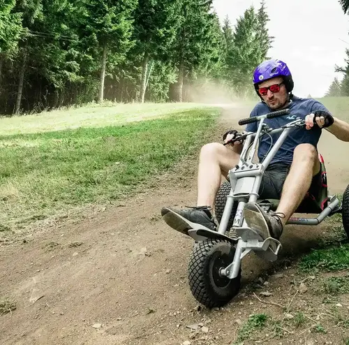 vermietung-altenberg-erzgebirge-sachsen-03.webp Eine männliche Person fährt mit einem Mountainkart konzentriert den Skihang hinunter.