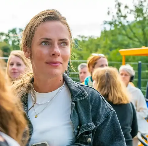 firmenevents-altenberg-erzgebirge-sachsen-40.webp Eine Frau steht inmitten einer großen Schlange von Menschen am Erlebnisberg Altenberg.