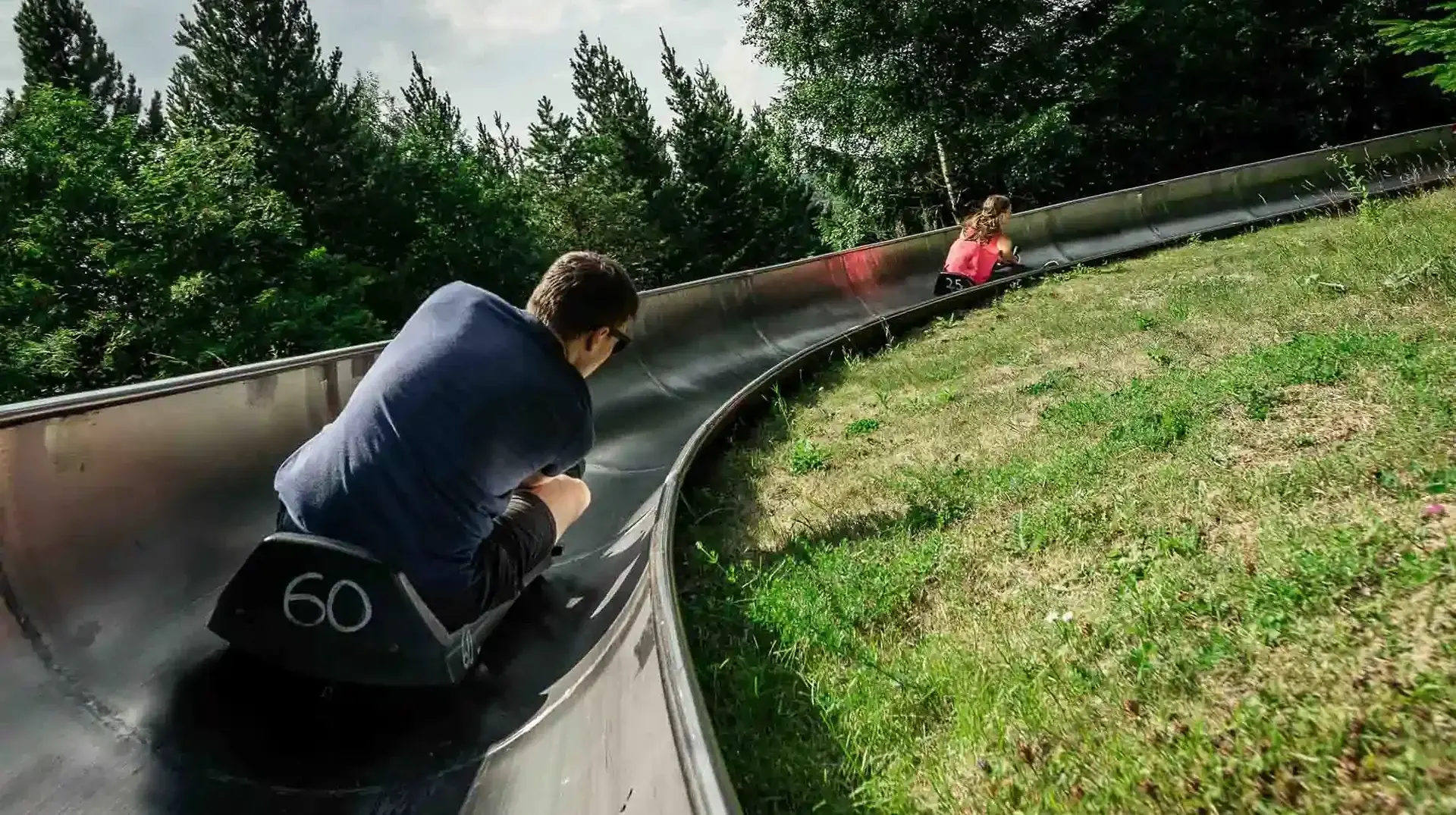 vermietung-feiern-geburtstag-betriebsfeier-erlebnisberg-altenberg-1.webp Zwei Personen rodeln zusammen am Erlebnisberg Altenberg.