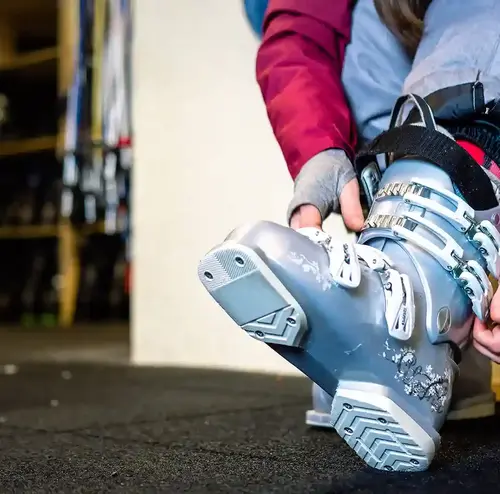 Eine Person zieht am Skiverleih Altenberg ihre Skischuhe an.