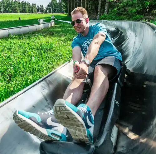 wandergruppen-altenberg-erzgebirge-sachsen-10.webp Ein Mann sitzt alleine im Rodelschlitten im Freizeitpark Altenberg.