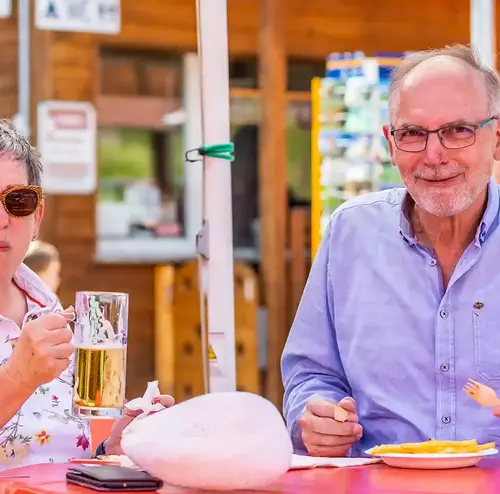 reisegruppen-altenberg-erzgebirge-sachsen-24.webp Ein Mann und eine Frauen essen und trinken an der Rodelklause im Freizeitpark Altenberg.