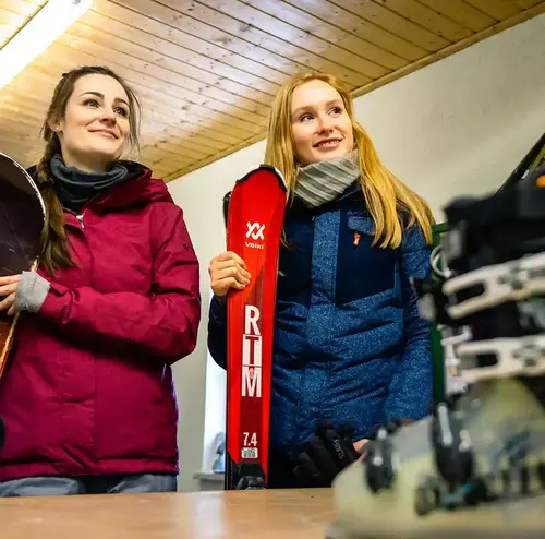 Zwei junge Frauen stehen geduldig im Skiverleih am erlebnisberg in Altenberg.