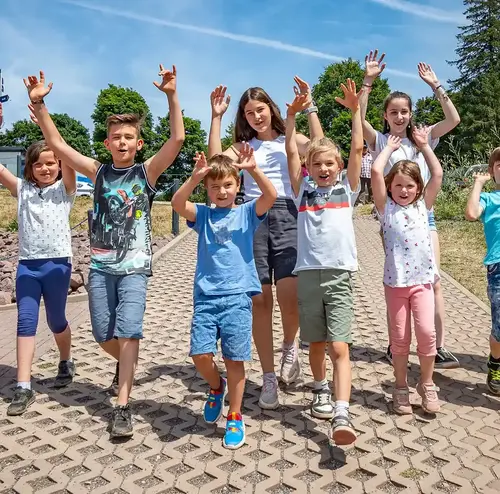 vereine-altenberg-erzgebirge-sachsen-33.webp Eine große Gruppe von Kindern heben am Parkplatz des Erlebnisberg Altenberg.