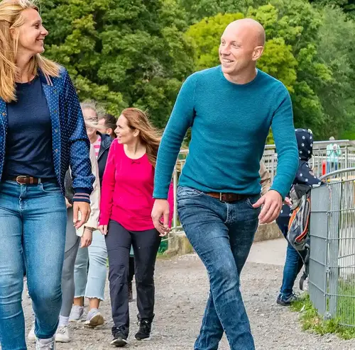 reisegruppen-altenberg-erzgebirge-sachsen-26.webp Eine Reisegruppe läuft fröhlich einen geschotterten Weg im Freizeitpark Altenberg entlang.