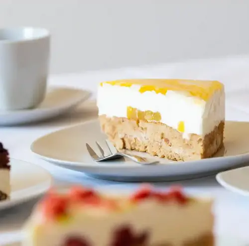 Man sieht leckere und frische Kuchenstücke, die neben Tassen stehen. Die Kuchenstücke sind alle unterschiedlich und frisch gebacken. Entdecken sie leckere Snacks, sowie Kaffee und Kuchen in der Rodelklause am Erlebnisberg in Altenberg.