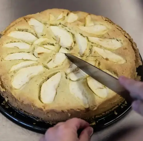 Man sieht einen frisch gebackenen Apfelkuchen, der gerade angeschnitten wird. Entdecken sie frisch gebackene Kuchenspezialitäten in der Rodelklause am Erlebnisberg in Altenberg. 