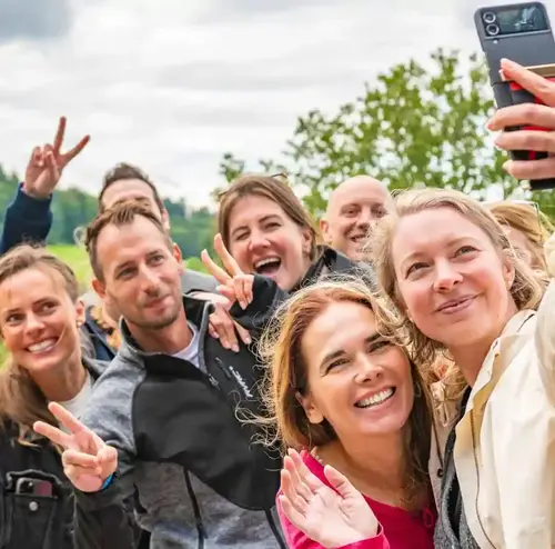 Eine junge Frau macht ein Selfie von sich und ihrer Reisegruppe. Alle sind am lachen und genießen die Natur. Erleben sie schöne Momente und tolle Gruppenangebote am Erlebnisberg in Altenberg.