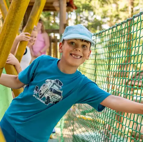 schulklassen-im-sommer-altenberg-erzgebirge-sachsen-39.webp Ein kleiner Junge klettert lachend auf einem Kinderspielplatz am Erlebnisberg Altenberg.