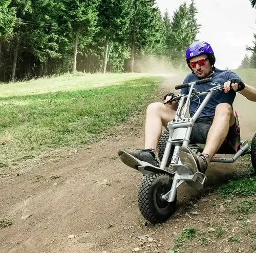 wandergruppen-altenberg-erzgebirge-sachsen-03.webp Mit voller Konzentration fährt ein junge Mann mit dem Mountainkart einen Berg hinunter.