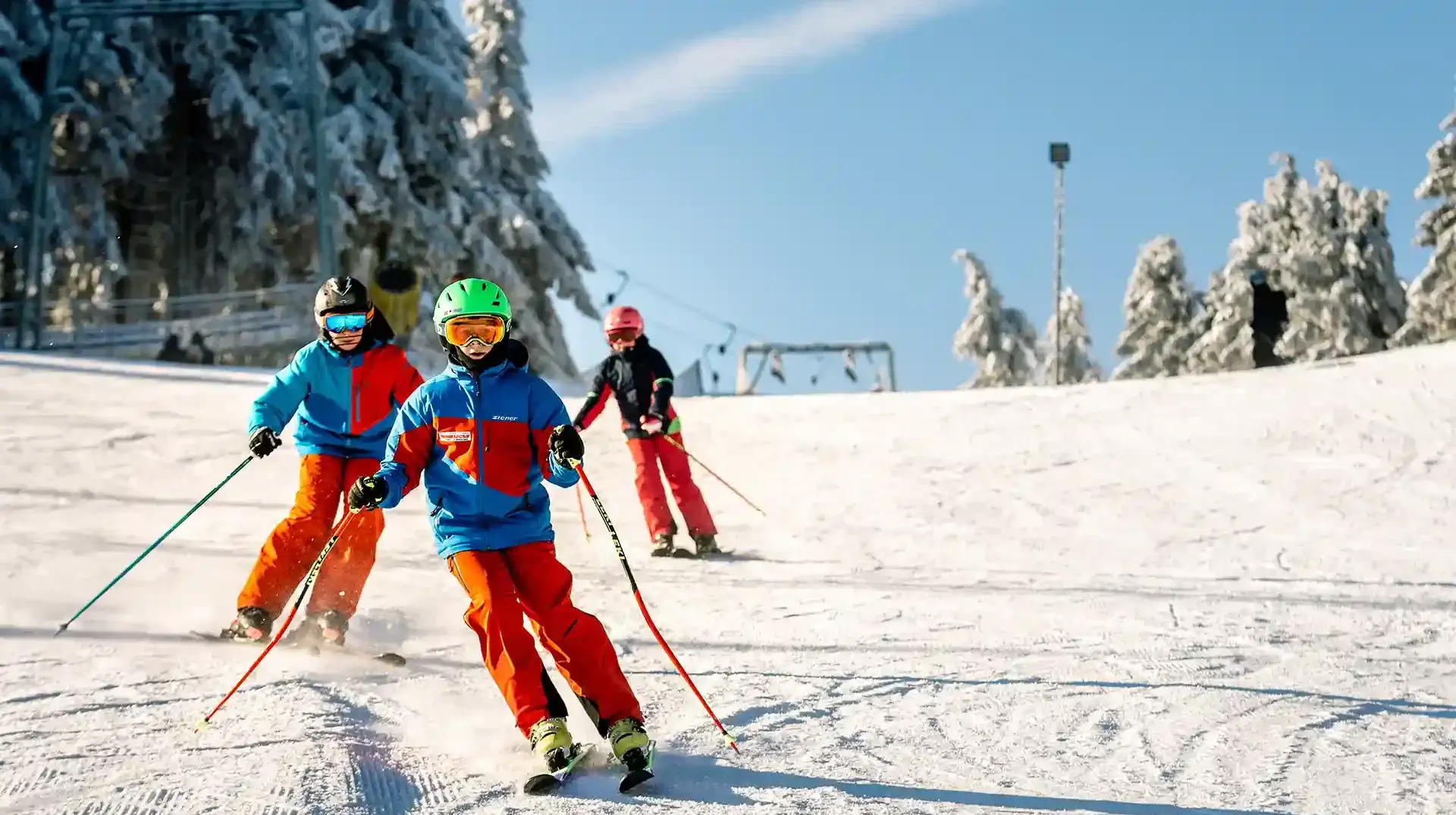 schulklassen-im-winter-altenberg-erzgebirge-sachsen-05.webp Drei Kinder einer Schulklasse fahren konzentriert die Skipiste am Freizeitpark Altenberg hinunter.