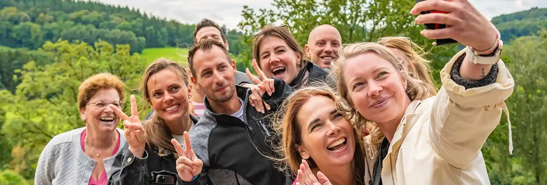firmenevents-altenberg-erzgebirge-sachsen-39.webp Besucher eines Firmenevents machen lachend ein Selfie am Erlebnisberg Altenberg