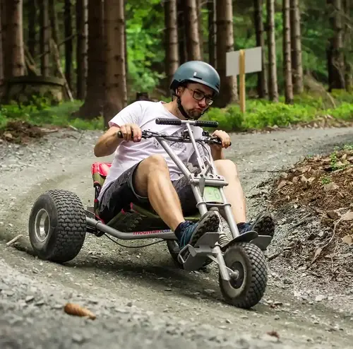 vermietung-altenberg-erzgebirge-sachsen-22.webp Ein junger Mann fährt im einem Wald im Erzgebirge mit einem Mountainkart.
